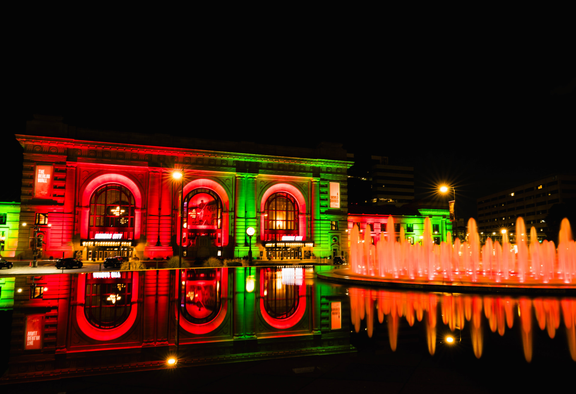 Union Station lit red and green, mirrored in still water