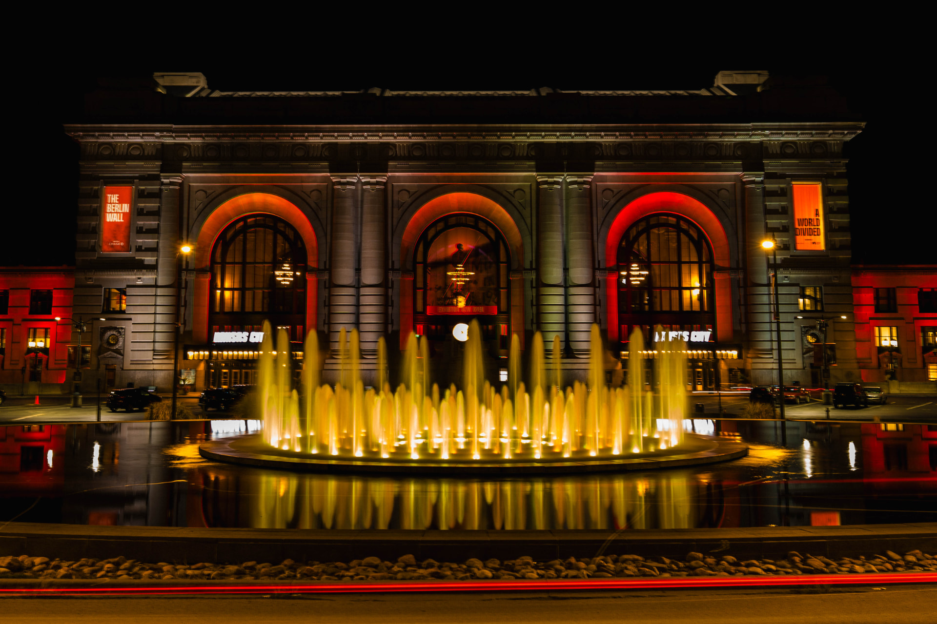 Union Station at night, red-lit arches above a golden fountain