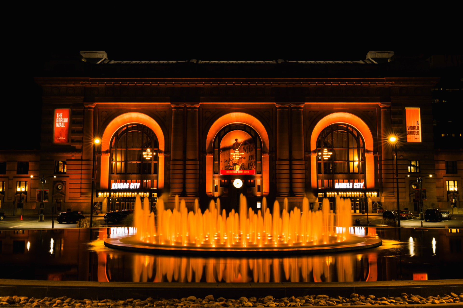 Union Station glowing orange behind an illuminated fountain