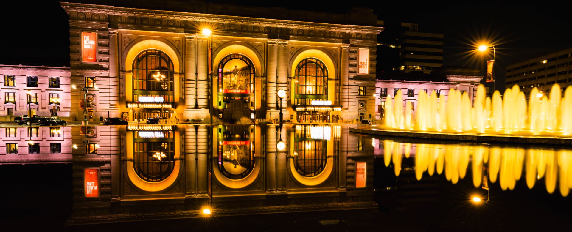 Union Station in gold light, reflected in the water beside the fountain